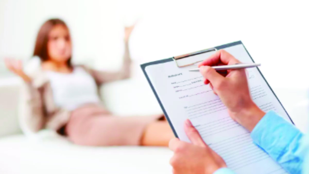 Psicóloga fazendo anotações durante sessão de psicoterapia com mulher, representando escuta e acolhimento.