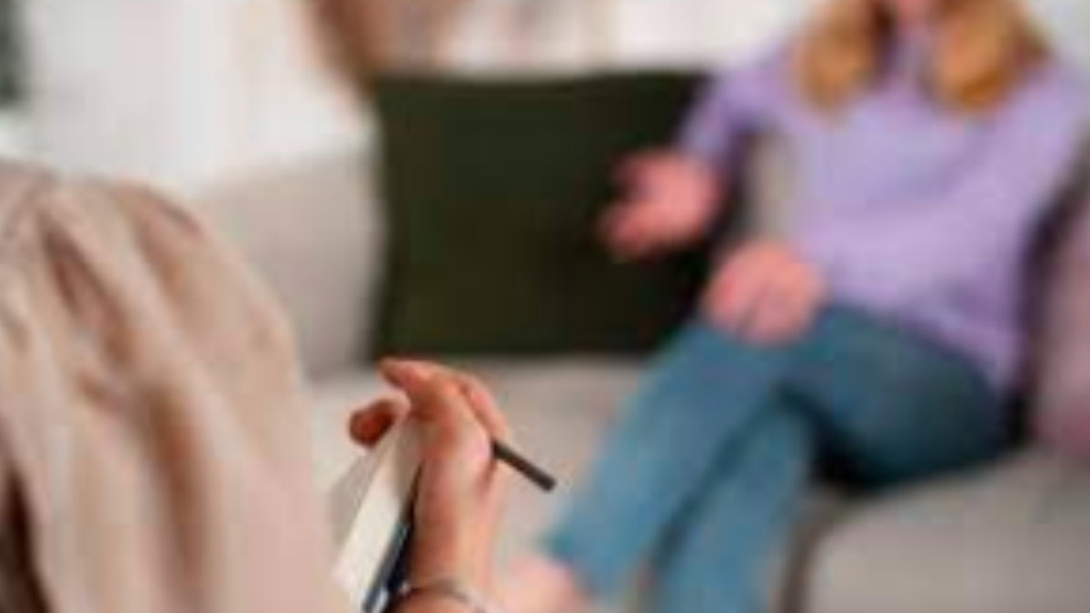 Psicóloga em sessão de psicoterapia, escutando paciente em ambiente acolhedor e reservado.
